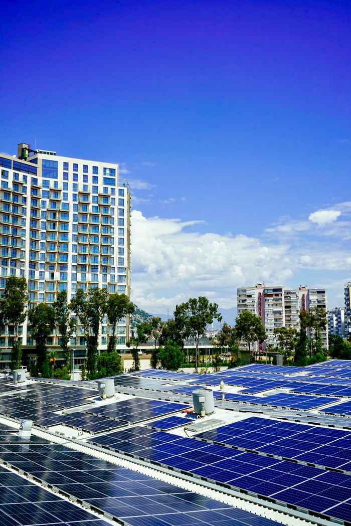 creative-approach-img High-rise buildings and a large solar panel array under a clear blue sky.